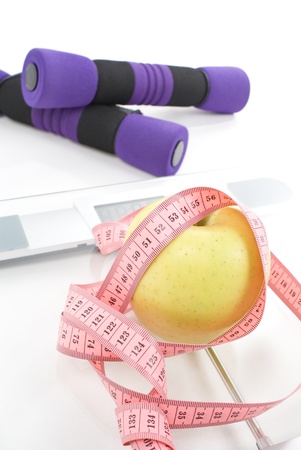 Apple tighten with measure tape, dumbbell, and scale isolated on white の写真素材