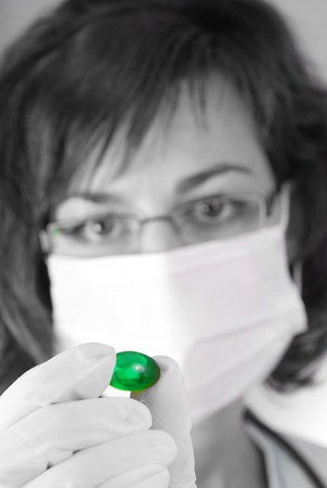 Confident female doctor holding a green pill in black and whiteの写真素材