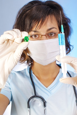 Confident female doctor holding a green pill and a syringeの写真素材