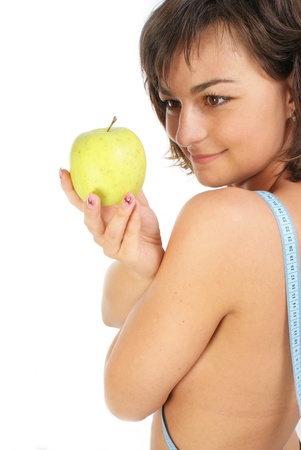  Young girl with measuring tape around slim beautiful waist and holding an appleの写真素材