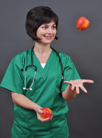 Attractive lady doctor and fresh apples on gray background の写真素材