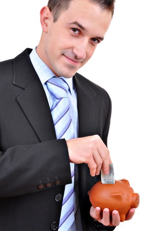 Close up of a man inserting a coin into a piggy bank isolated on white background の写真素材