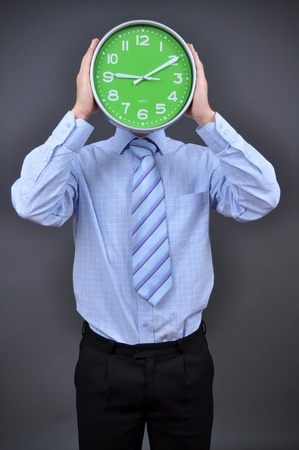 Businessman holding a hour on grey backgroundの写真素材