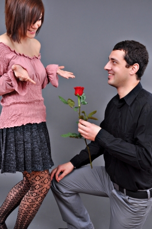 happy beautiful teenage couple, a boy giving a rose to his girlfriendの写真素材
