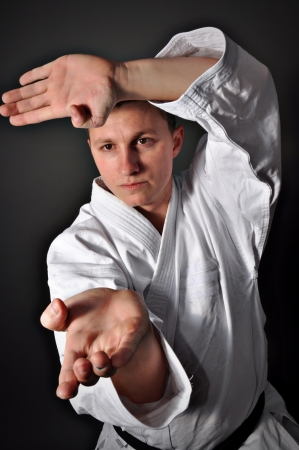 Young sporty karate man doing special exercise on gray background の写真素材