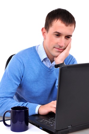Young man reading on laptop, drinking tea or coffeeの写真素材