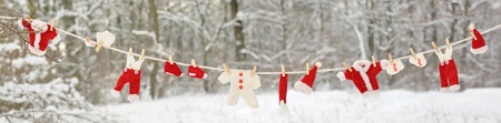 Red santa claus clothes drying in the open air hanging on clothes line affixed with wooden pegs の写真素材