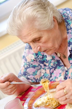 Happy old gray-haired woman eatingの写真素材