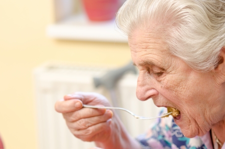 Happy old gray-haired woman eatingの写真素材