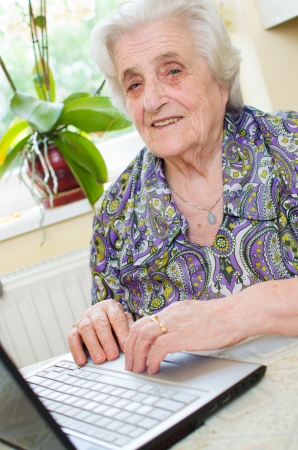 The senior hand presses the laptop keyboard button の写真素材