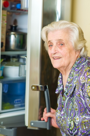 old woman looking for food in the refrigerator の写真素材