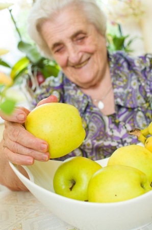 Happy old gray-haired woman with fruitsの写真素材