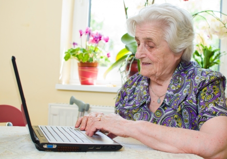 The senior hand presses the laptop keyboard button の写真素材