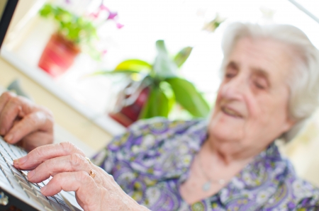 The senior hand presses the laptop keyboard button の写真素材