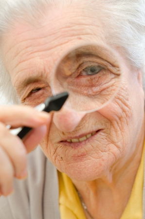 Happy old gray-haired woman with magnifierの写真素材