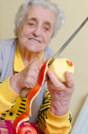 senior woman cutting fresh applesの写真素材