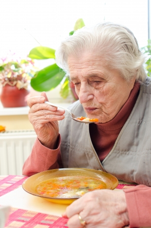Happy old gray-haired woman eating soupの写真素材