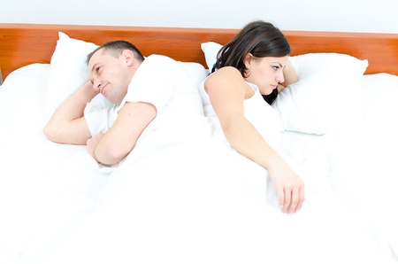 A young couple in bed having problemsの写真素材