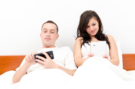 An attractive caucasian couple using their tablet in their bedroomの写真素材