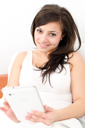 Touch screen tablet computer - woman in her bedの写真素材