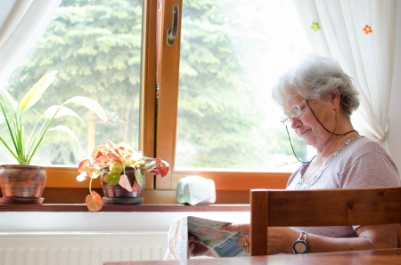 Woman in living room reading newspaper の写真素材