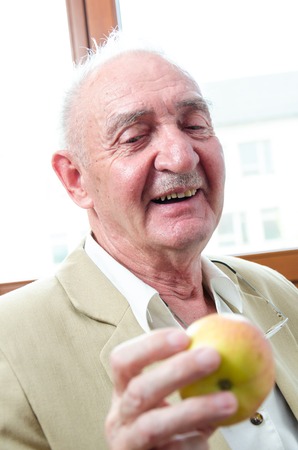 Closeup profile on a smiling old man with appleの写真素材