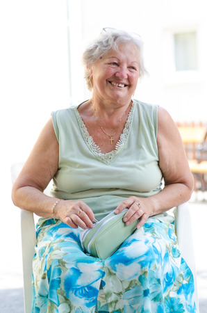 Happy old woman sitting and relaxing in the natureの写真素材