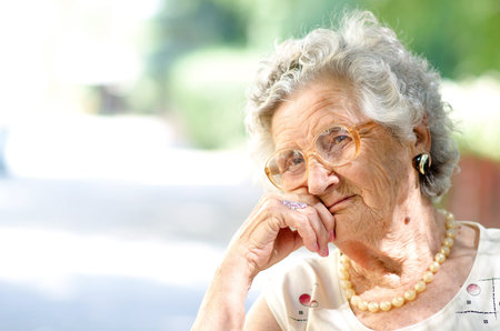 Portrait of the smiling elderly woman, sitting outdoor 