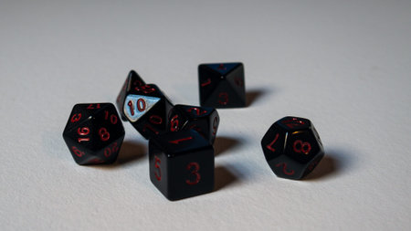 A twenty-sided dice thrown onto a white surface. Dice in black and red colors. White background.