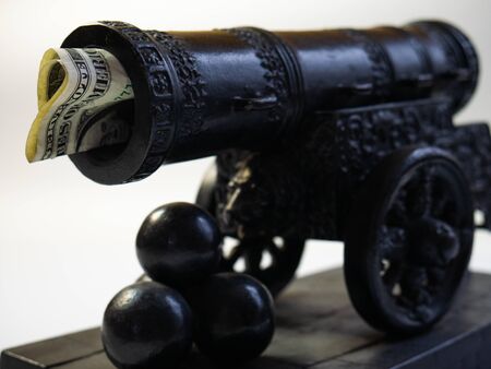 The money's stuck in the gun. Cannon shot with money. Empty waste of money. Gun shooting kernels in miniature.の写真素材