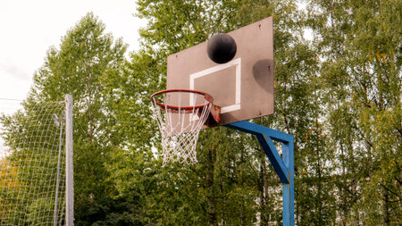 School basketball court. A black basketball is flying in the ring.