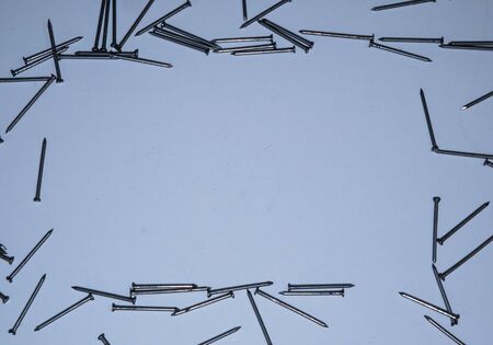 Flat lay nails on a white background. Frame for text. Construction tools, the theme of construction. A place to text. Hobnails and pins.の写真素材