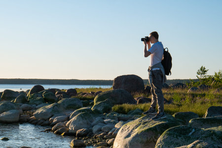 The photographer stands on the stone coast and shoots it. Photographer's job. Beautiful birch with...