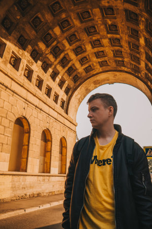 A man looks down against the backdrop of a large old arch. A large historical arch.の写真素材