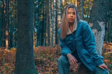 A beautiful girl in the autumn orange forest. Fashionable woman pink top and jeans in the back...
