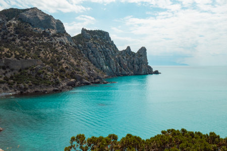 A nature scenery of a calm sea and green bushes, with Lions Head mountain in the horizon. Landscape of the ocean near the mountains with blue cloud sky and copy space. High quality photoの写真素材