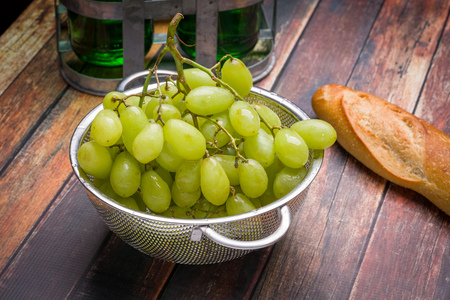 Fresh grapes in stainless steel colander on a wood surfaceの写真素材