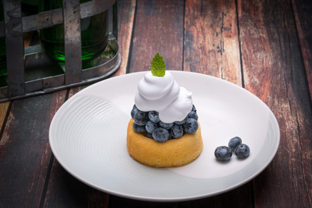 Fresh blueberries on a small cake with whipped creamの写真素材