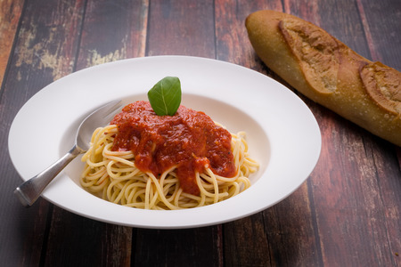 Spaghetti with marinara in a white bowl on a wood surfaceの写真素材
