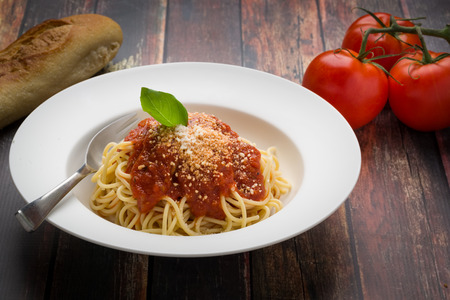 Spaghetti with marinara in a white bowl on a wood surfaceの写真素材