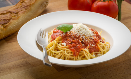 Spaghetti with marinara in a white bowl on a wood surfaceの写真素材