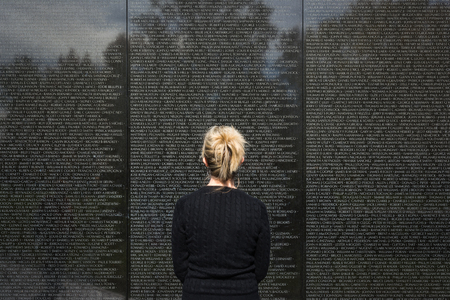 Woman Standing Looking At Names on Vietnam Memorial Washington DC Landmarkのeditorial素材
