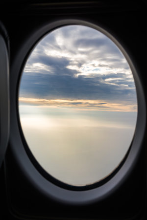 View of Foggy Overcast Clouds Sunlight Beams Rays Through Airplane Window Landscapeの写真素材