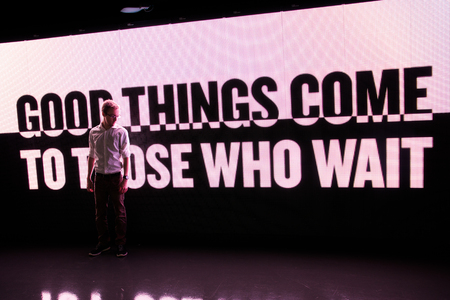 Young Man Standing on Wisdom Phrase LED Billboard Backgroundの写真素材