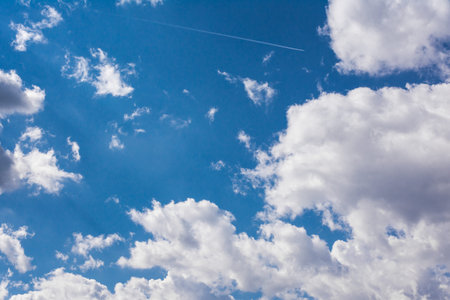 White Clouds Blue Sky Fluffy Sun Flare Airplane Trail  Sunny Daytime Texture Backgroundの写真素材
