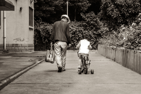 Child is riding on a bicycle in Chinaの写真素材
