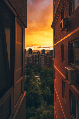 Looking Between Two Apartment Buildings at Cityscape Urban View Sunset Orange Red Afternoon Tight Vertical Spaceの写真素材