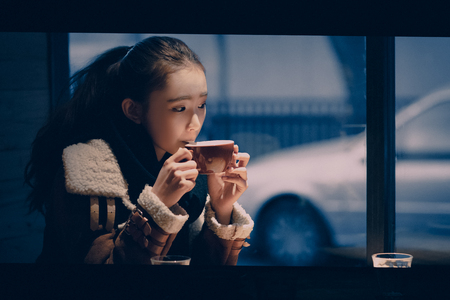 Asian Young Female Sitting Alone Drinking in Cafe Beverage Table Urban Windowの写真素材