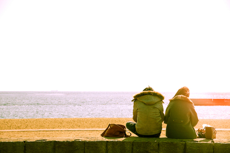 Couple sitting by the beach enjoying the viewの写真素材
