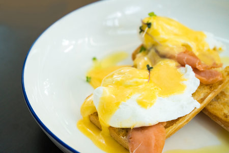 Egg Benedict with smoked salmon and fresh Hollandaise sauce on black backgroundの写真素材